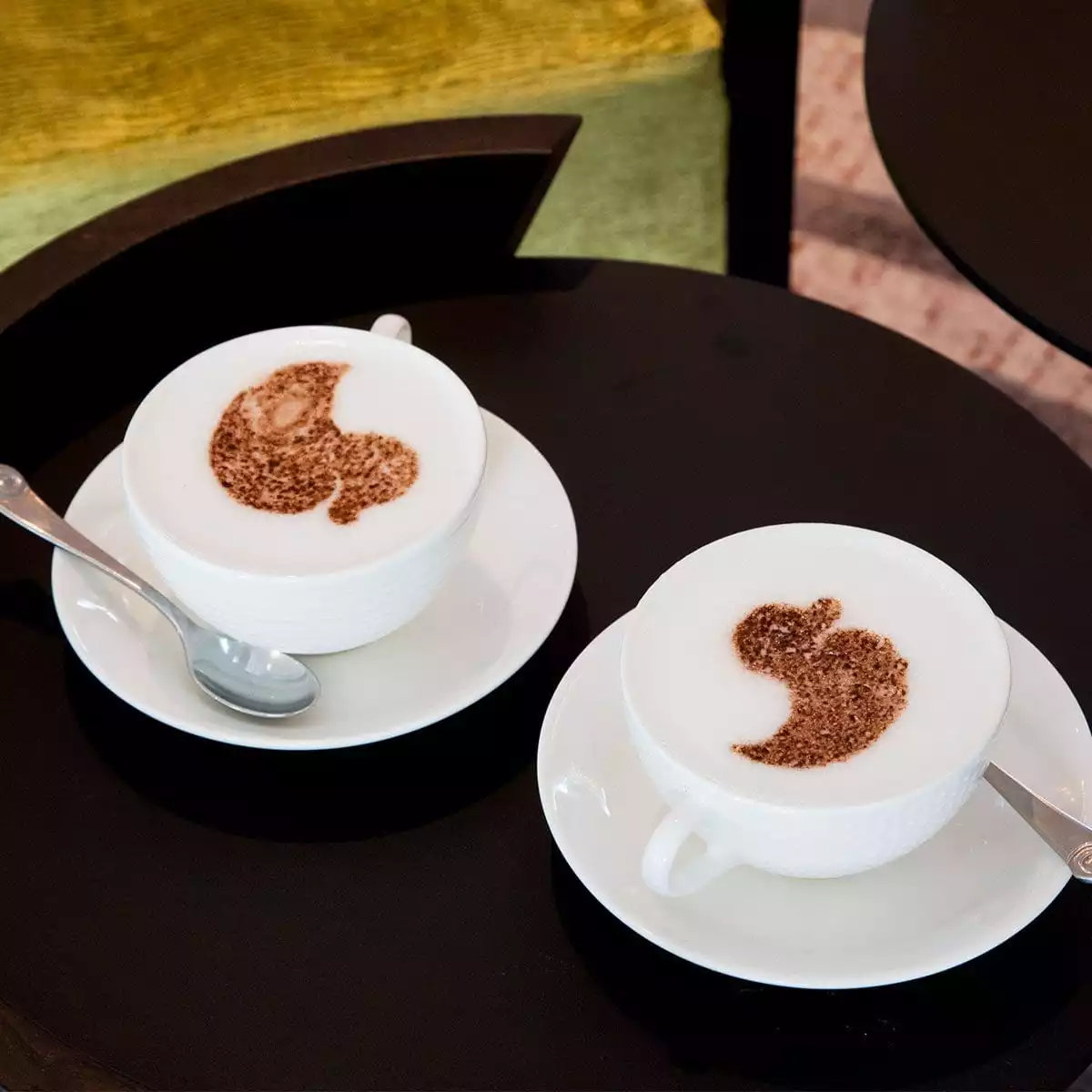 Two white coffee cups at The Runnymede on Thames with the duck logo sprinkled on the top using chocolate